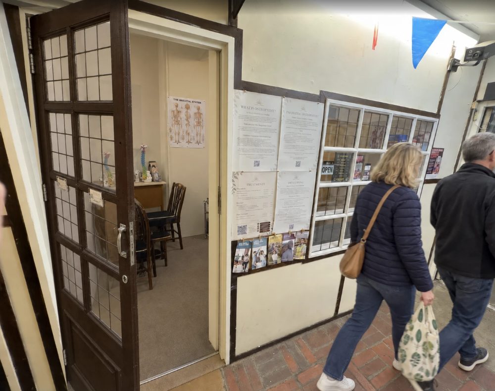 Malaya Therapies at unit A10, the treatment room through the open door with a skeleton chart on the wall, and osteopathy notices in the window beside it
