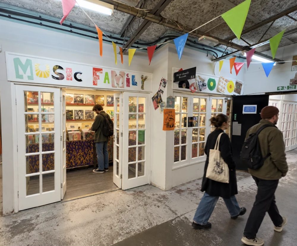 Music Family Records, cut-paper lettering above open white doors, racks of LPs inside and bunting across the corridor