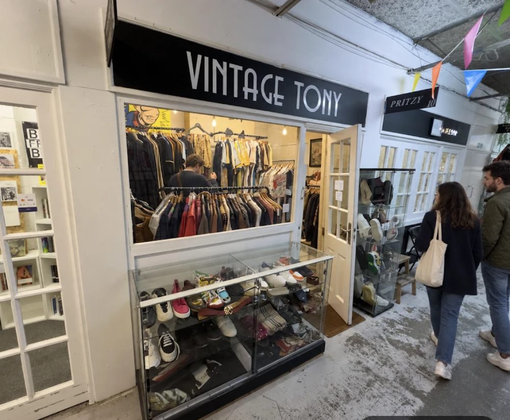 Vintage Tony, its name in white on a black fascia above a wide window of hanging jackets and shirts, with shoes and belts in the glass case below